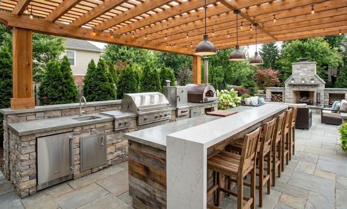 Outdoor kitchen with pergola and stone fireplace in Spring